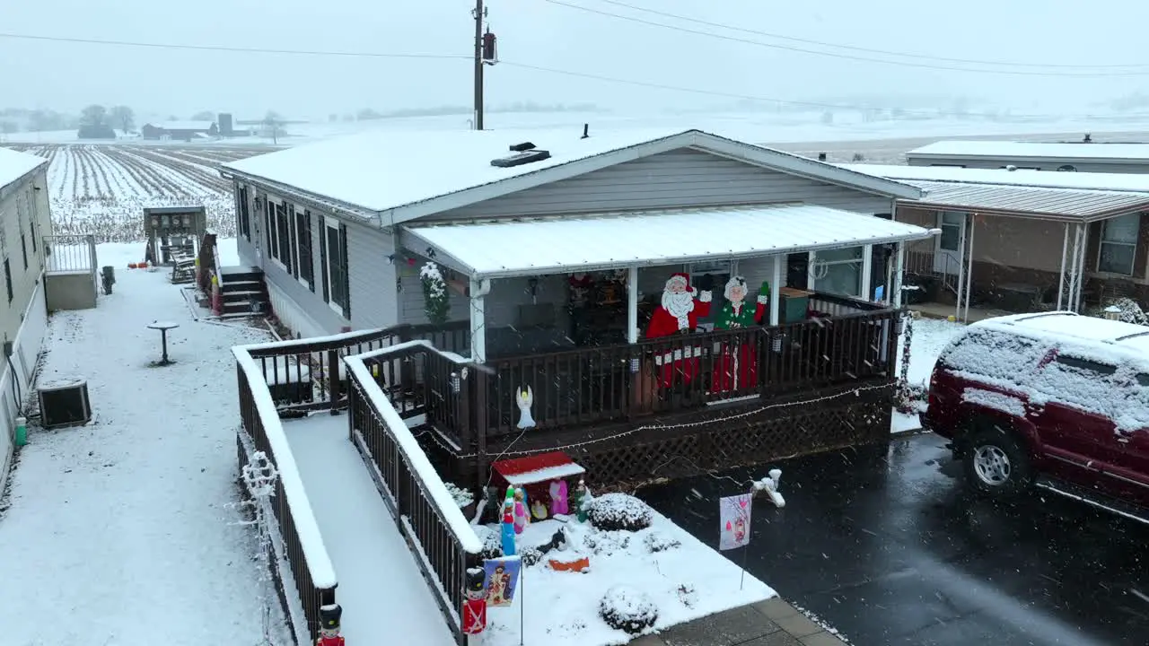 Santa and Christmas decorations during snow flurries in mobile home trailer park