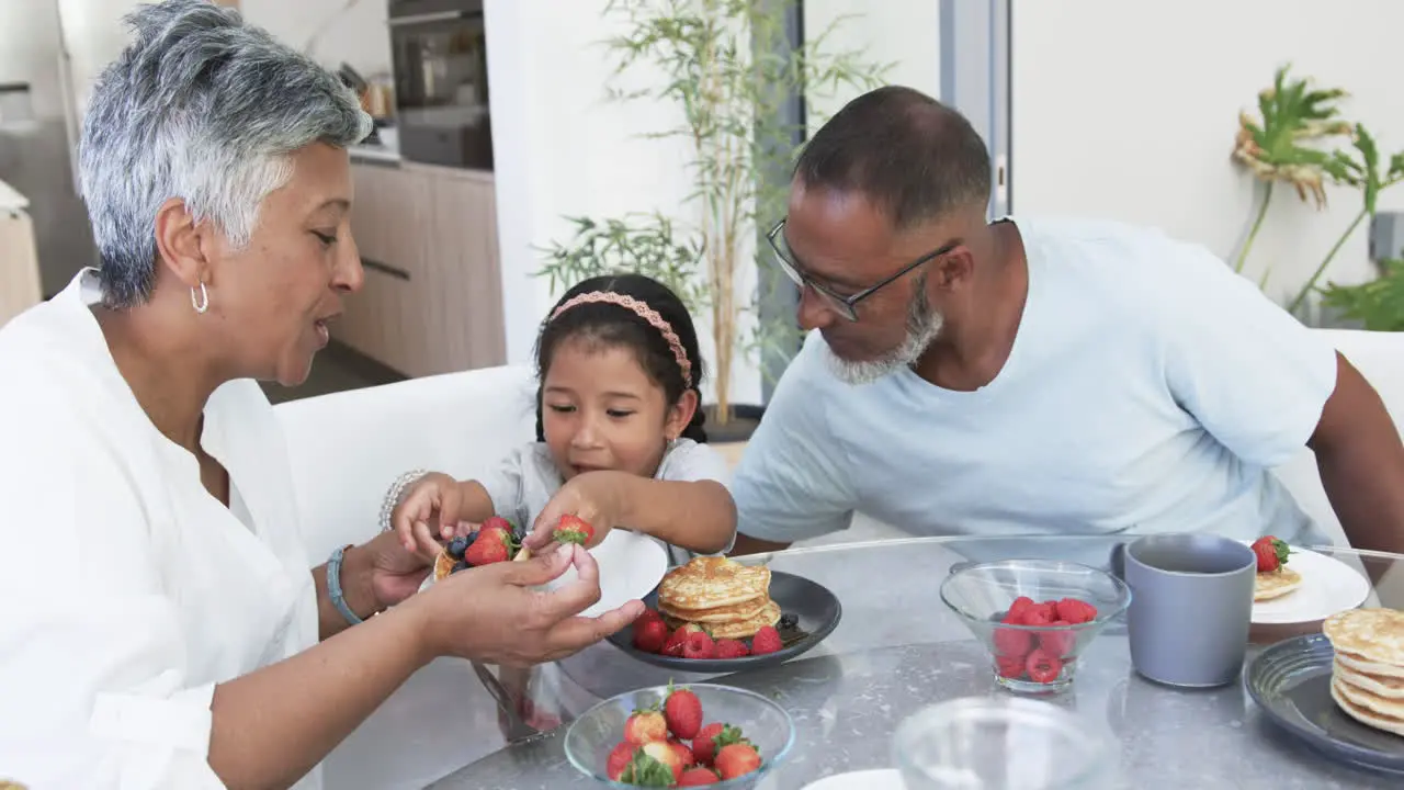 Biracial girl enjoys breakfast with her grandparents a biracial woman and man