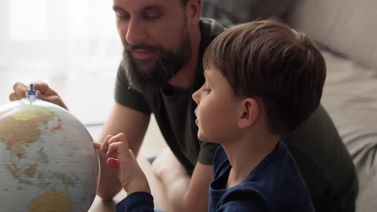 Handheld video of son and father looking at spinning globe