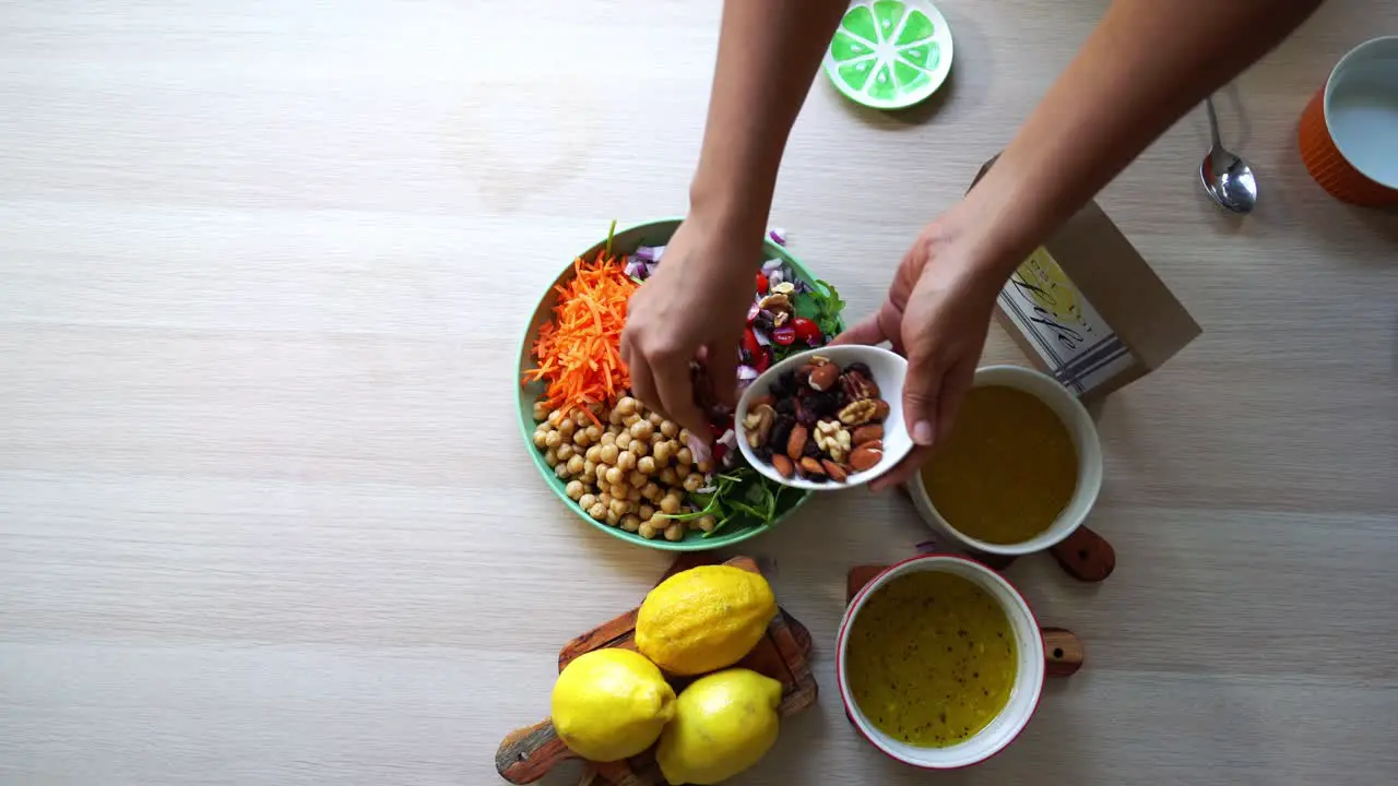 Adding nuts to chick pea salad aerial view of making a salad tomatoes carrots spinach chick peas lemons onions nuts dressing in view