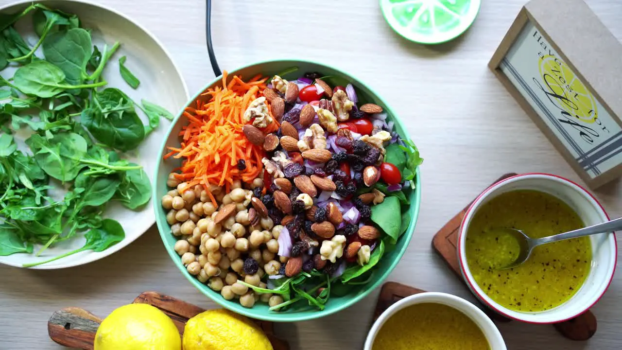 Aerial top view of chick peas salad assorted nuts tomatoes carrots spinach and salad dressing on the side