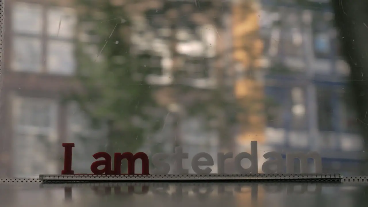 Window of moving tram with I amsterdam slogan