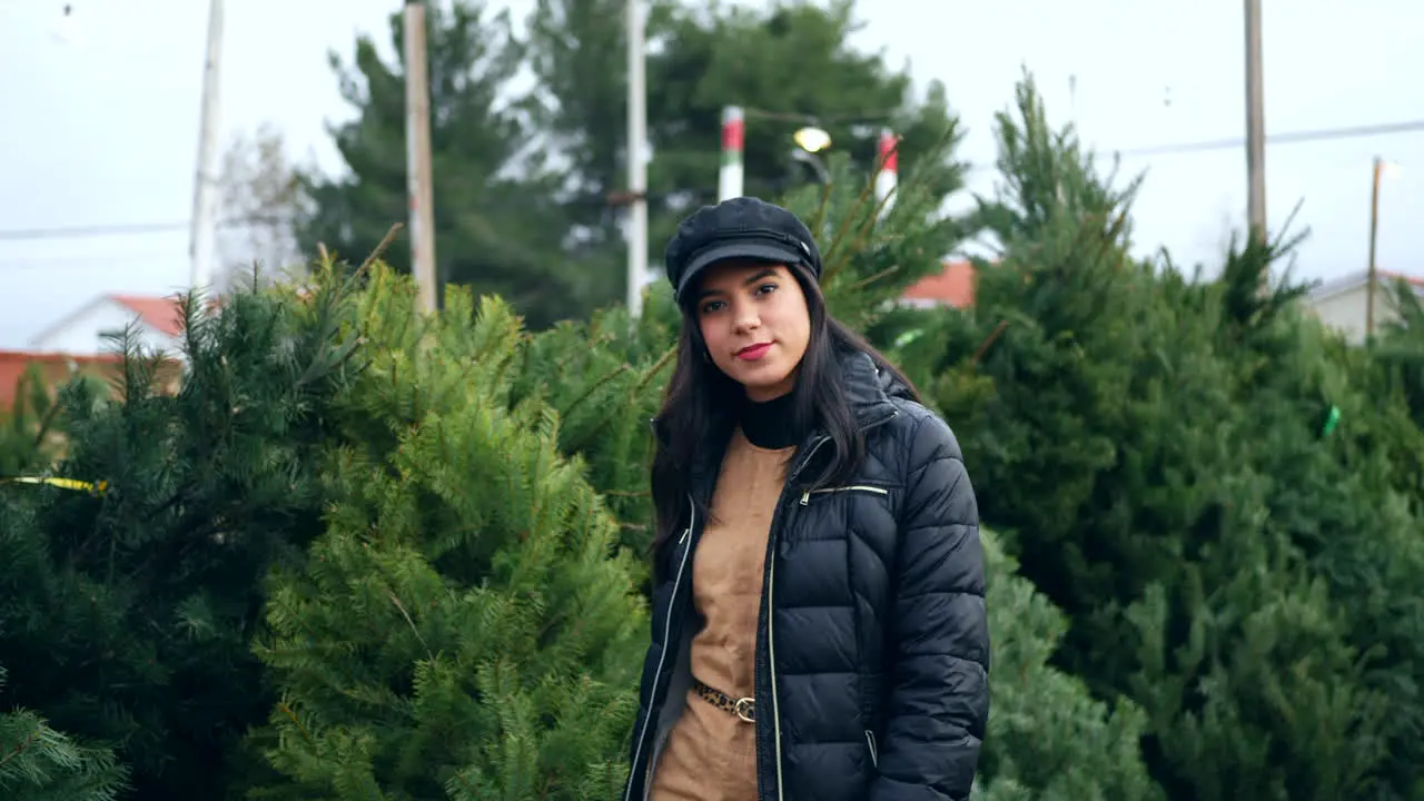 A beautiful woman in a happy holiday spirit smiling while shopping for festive douglas fir Christmas trees