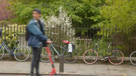 Wide Shot of Person On Electric Scooter Passing In Front of Bicycles