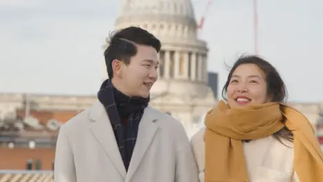 Young Asian Couple On Holiday Walking Across Millennium Bridge With St Pauls Cathedral In Background 4