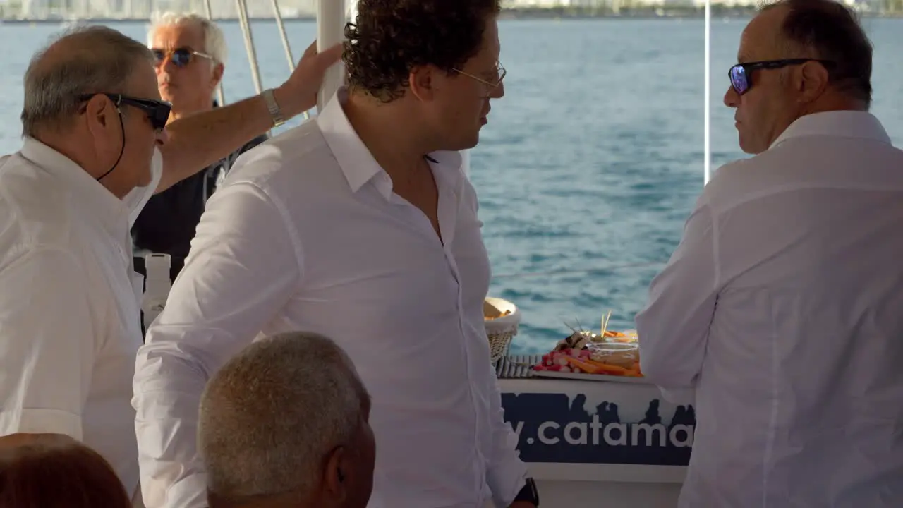 Groom walking through his wedding party talking to his guests on a sail boat