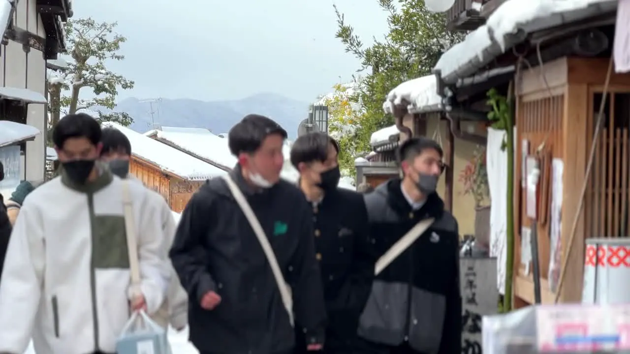 Young Male Friends on a Serene Stroll Through Kyoto's Snowy Streets During Snowfall