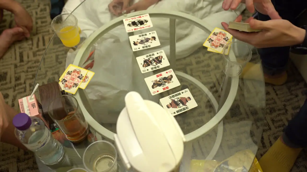 Group of Youngsters playing cards on a glass table in Hong Kong