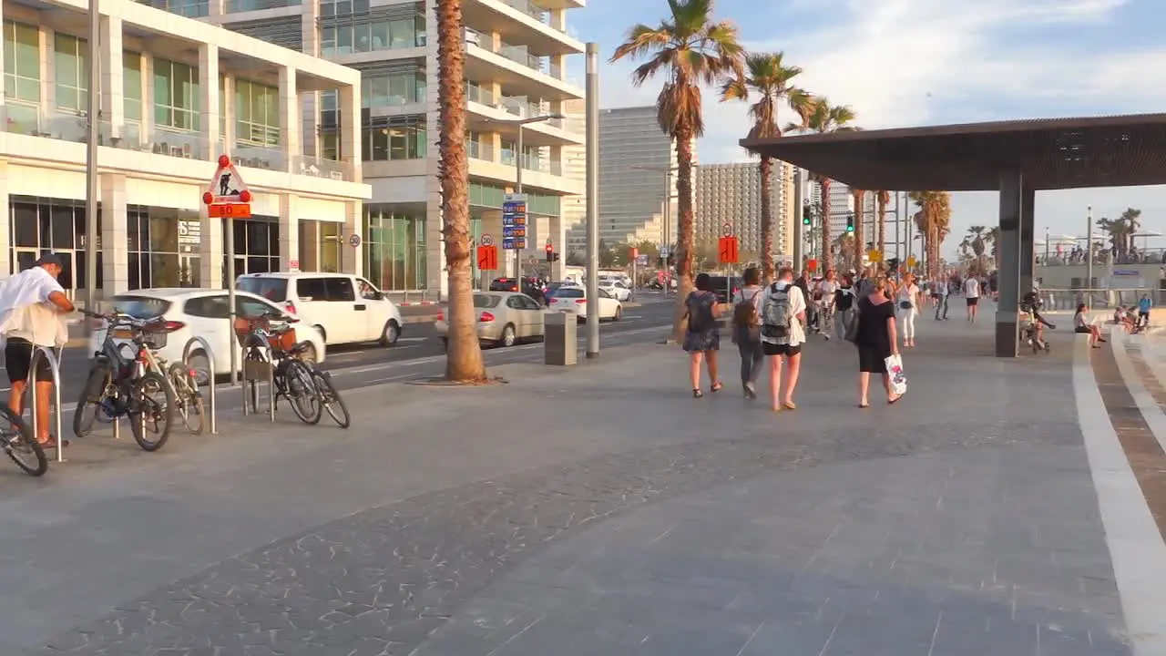 People walking on street on a pathway located near sea beach