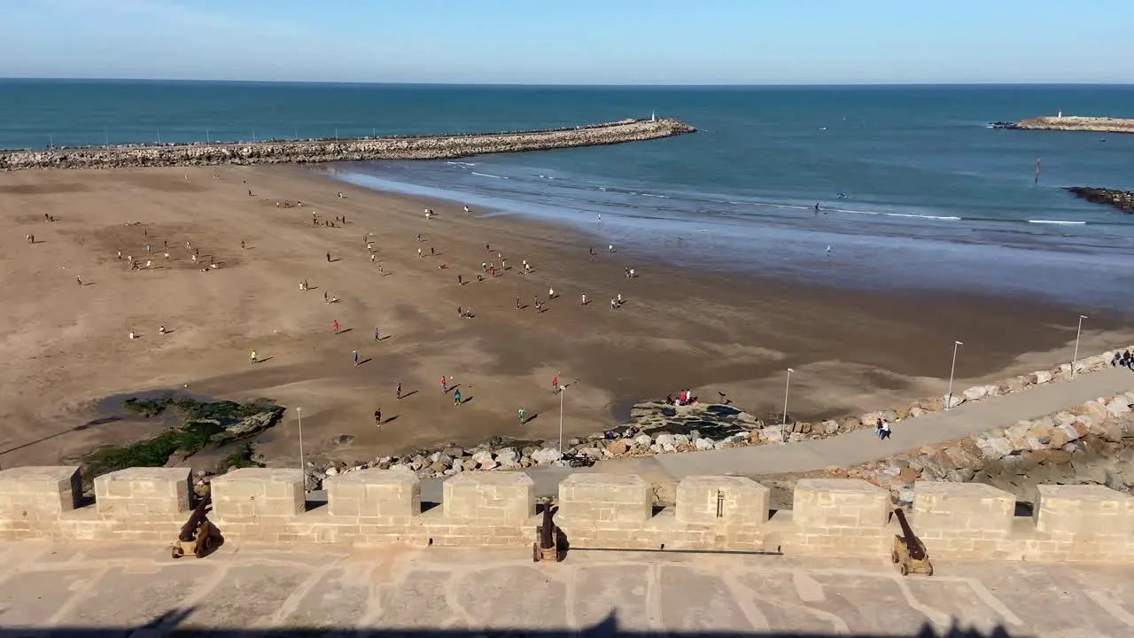 Many North African people playing happily in wide beach of Rabat at sunny day