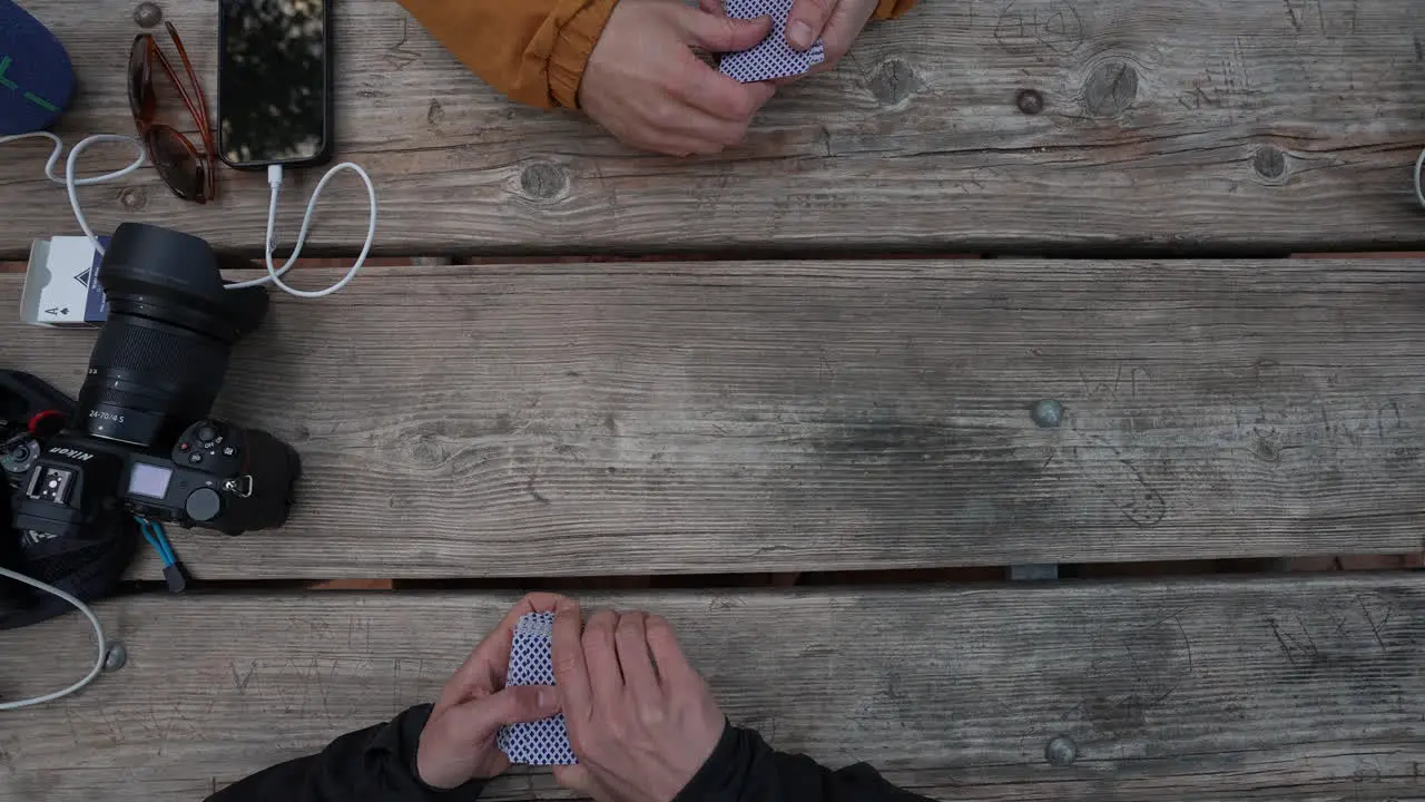 Two young men playing cards on a picnic table while camping