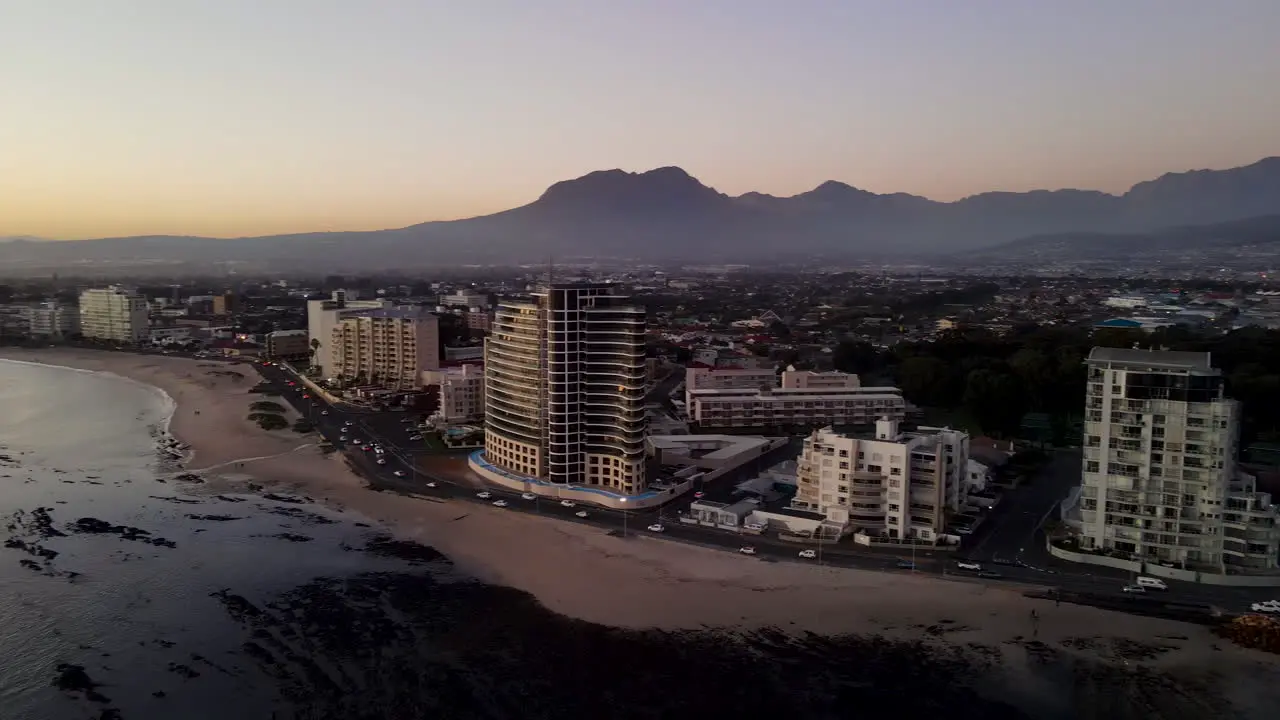 High angle sunset aerial pan of beachfront properties and long beach in Strand