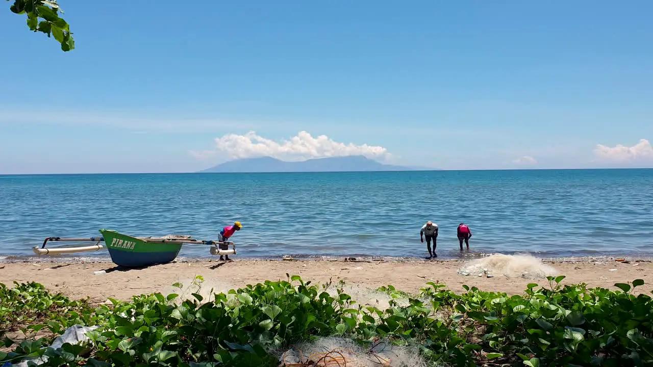 Local Timorese fishermen searching and looking for fishing bait along the sandy beach coastline of Dili Timor-Leste