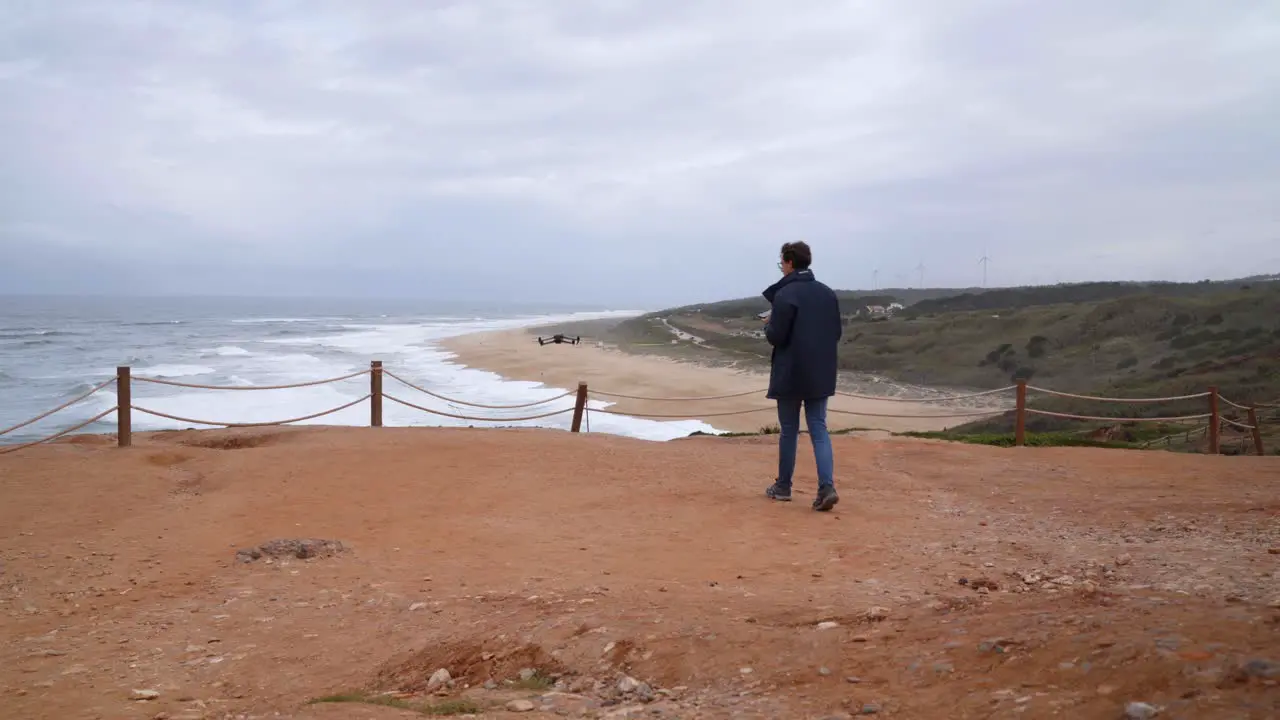 A Young traveller flying and taking off a drone at a Scenic beach of Nazare in Portugal