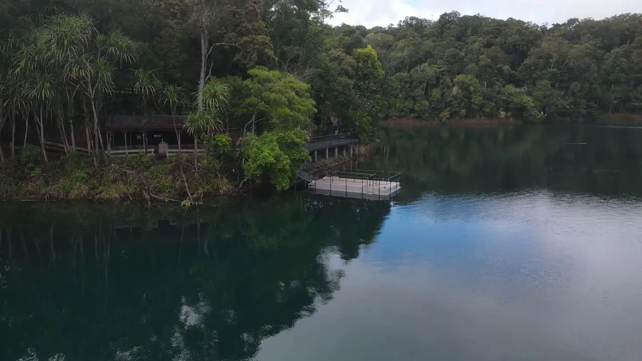 Aerial video showing a popular holiday area on a volcanic crater lake with a pontoon floating by the shore