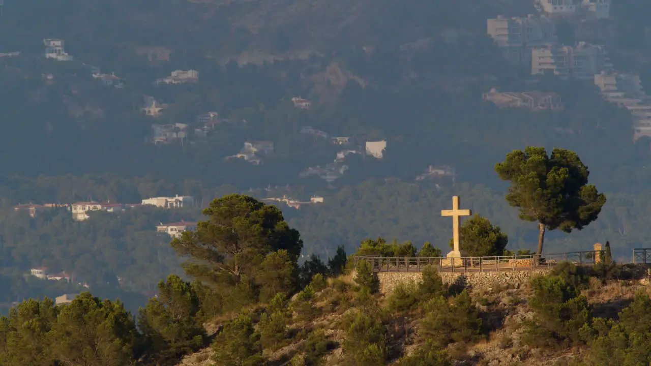 Scene of mountain town with Christian cross on the hill in La Nucia Spain