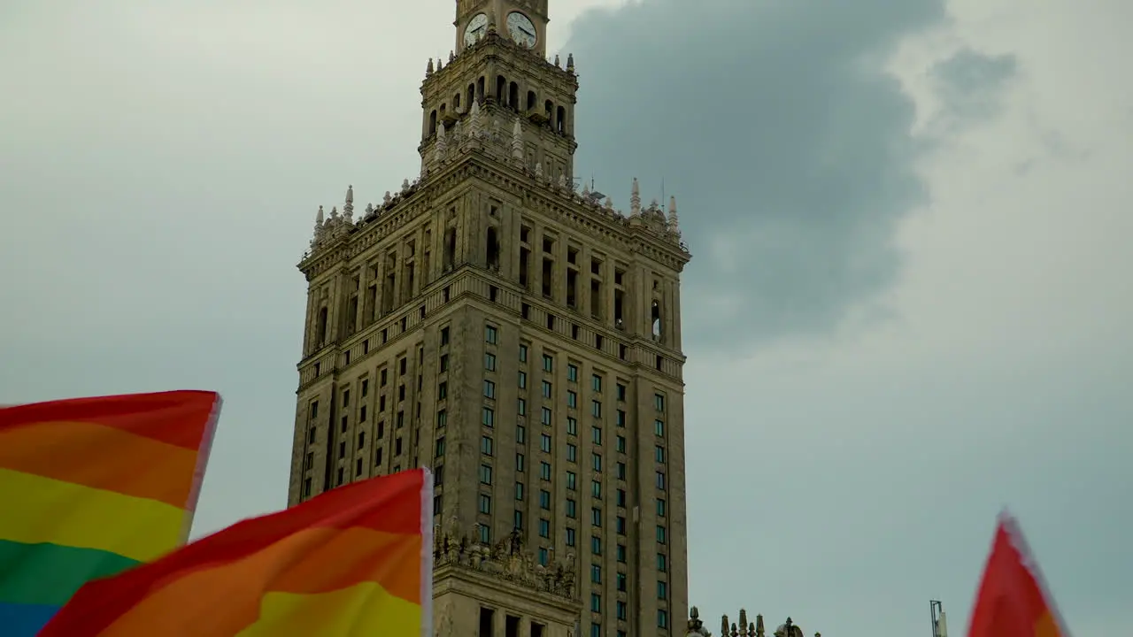 Waving Rainbow Flags And Clock Tower Of The Palace Of Culture And Science Against Dramatic Sky In Warsaw Poland