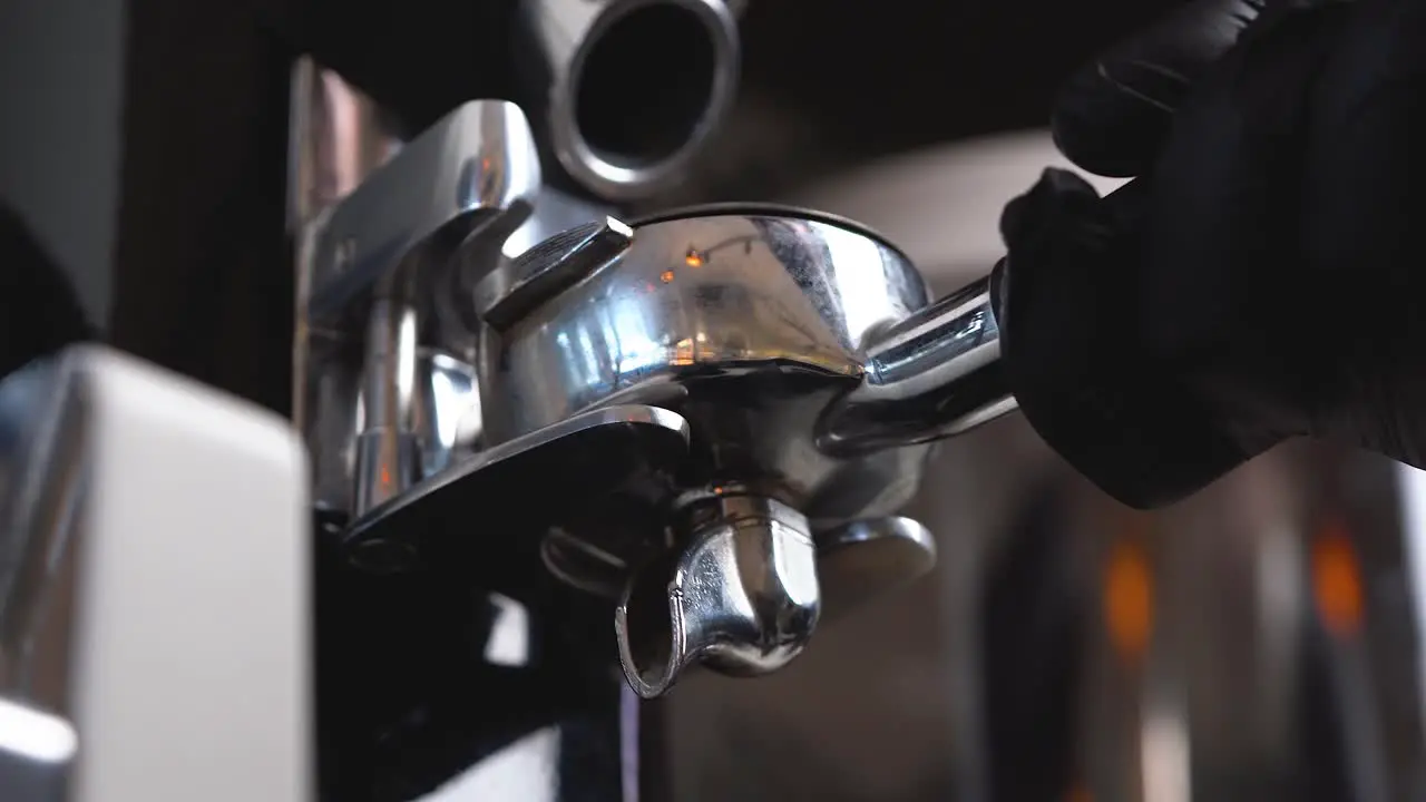 A barista adds ground coffee from a coffee bean grinder to a portafilter