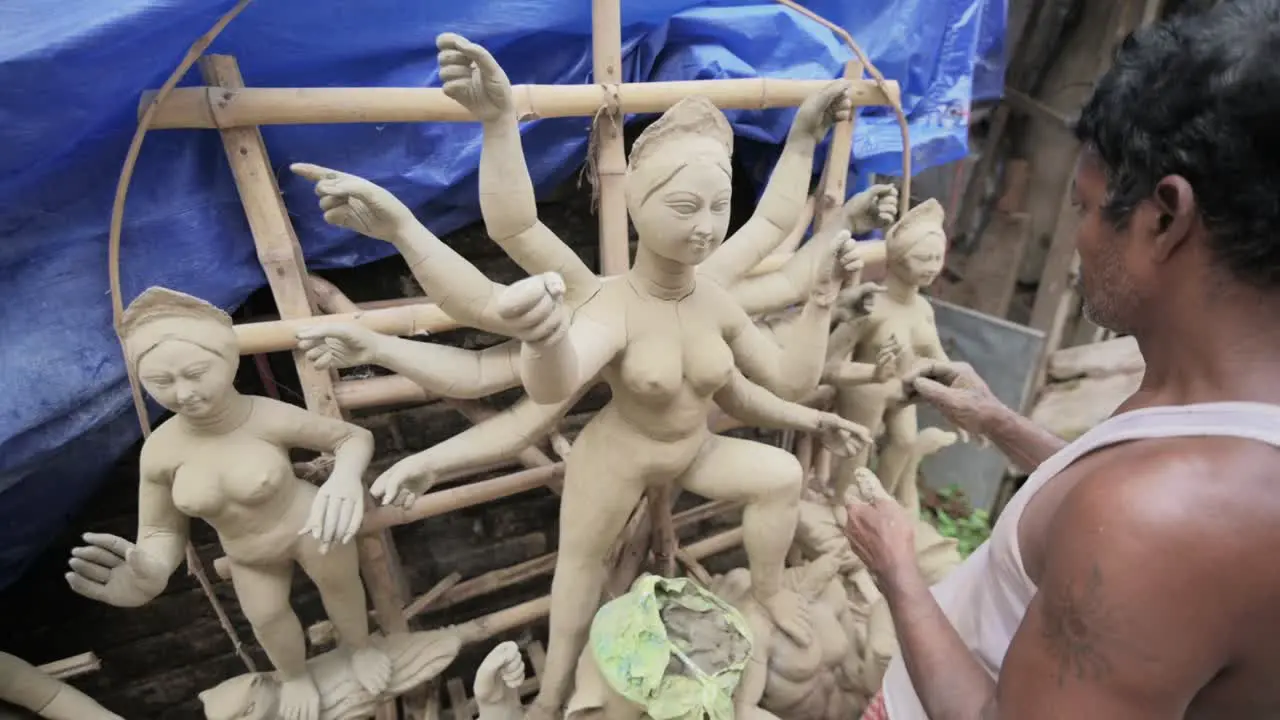 Poor artisan doing finishing touches to idols of Hindu goddess Durga with clay at Kumartuli slow motion track zoom in shot