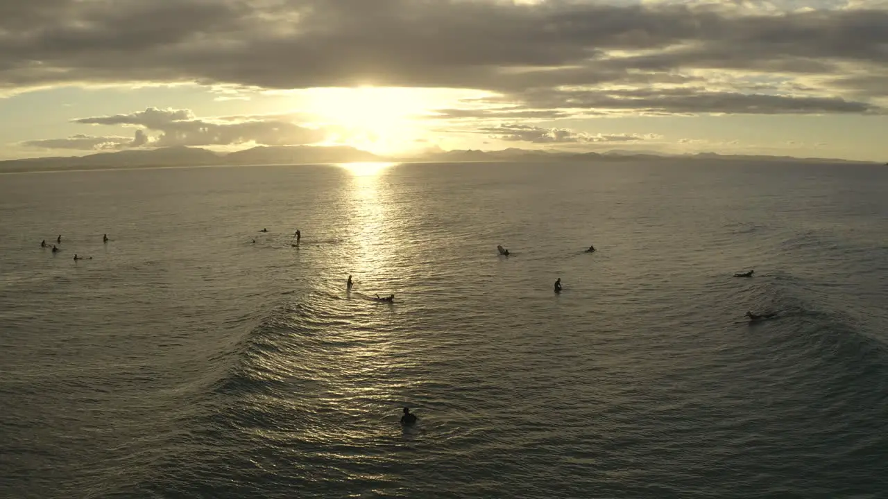 4k Static drone shot of a big group of people surfing during sunset at Byron bay Australia