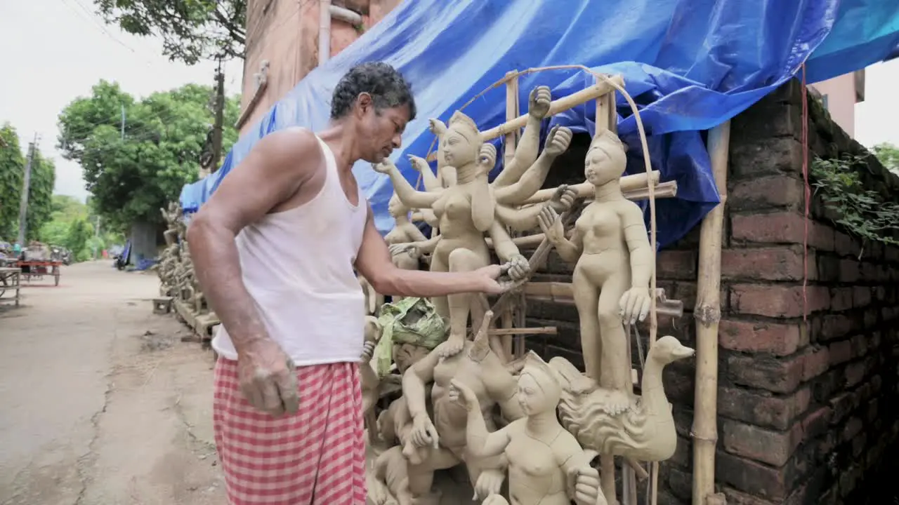 Poor Asian sculpture making idols of Hindu goddess Durga with clay slow motion track zoom in shot