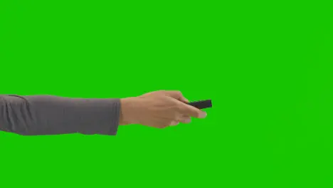 Studio Close Up Shot Of Woman Holding And Using TV Remote Control Against Green Screen