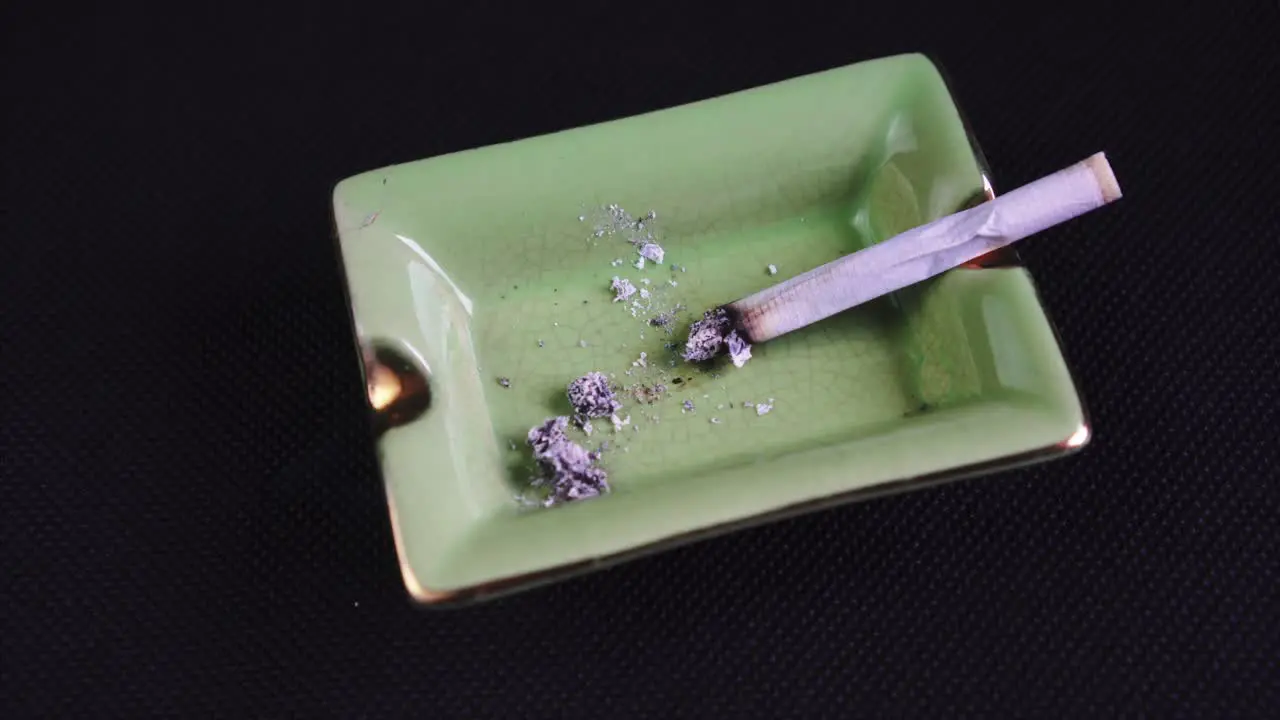 Smoking and Ashing a Rolled Cigarette or Joint legalised marijuana on green Ashtray