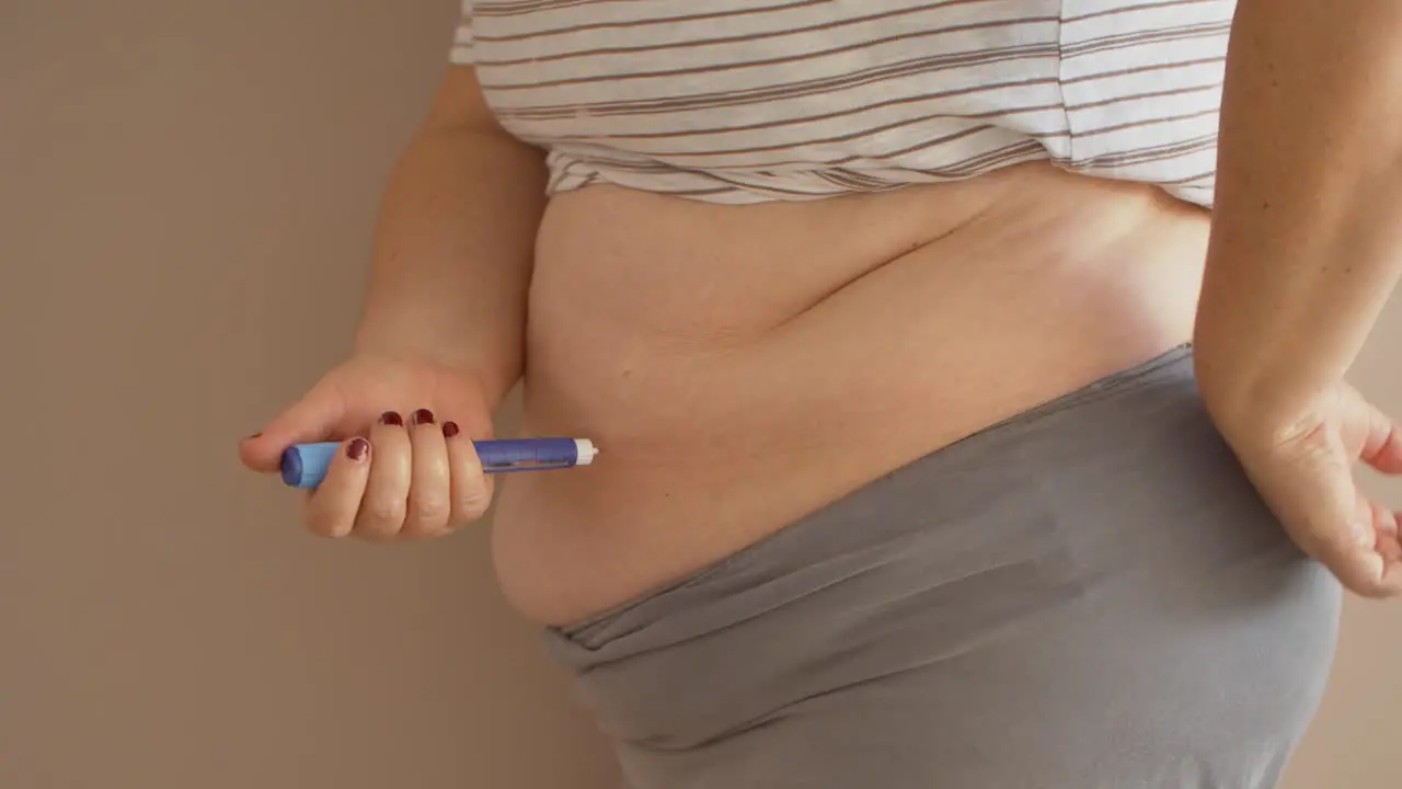 Overweight woman injecting diabetes medicine into her stomach