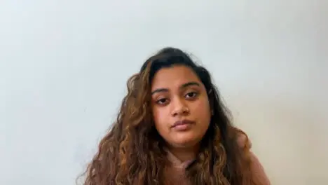 A Young Female Student Visibly Bored Whilst Looking Directly into Camera During Remote Lecture