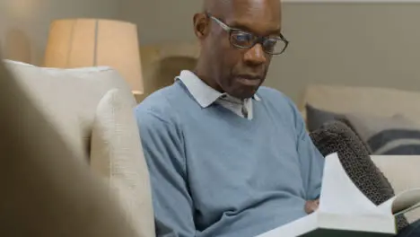 Middle Aged Man Sitting On a Sofa Reading a Book