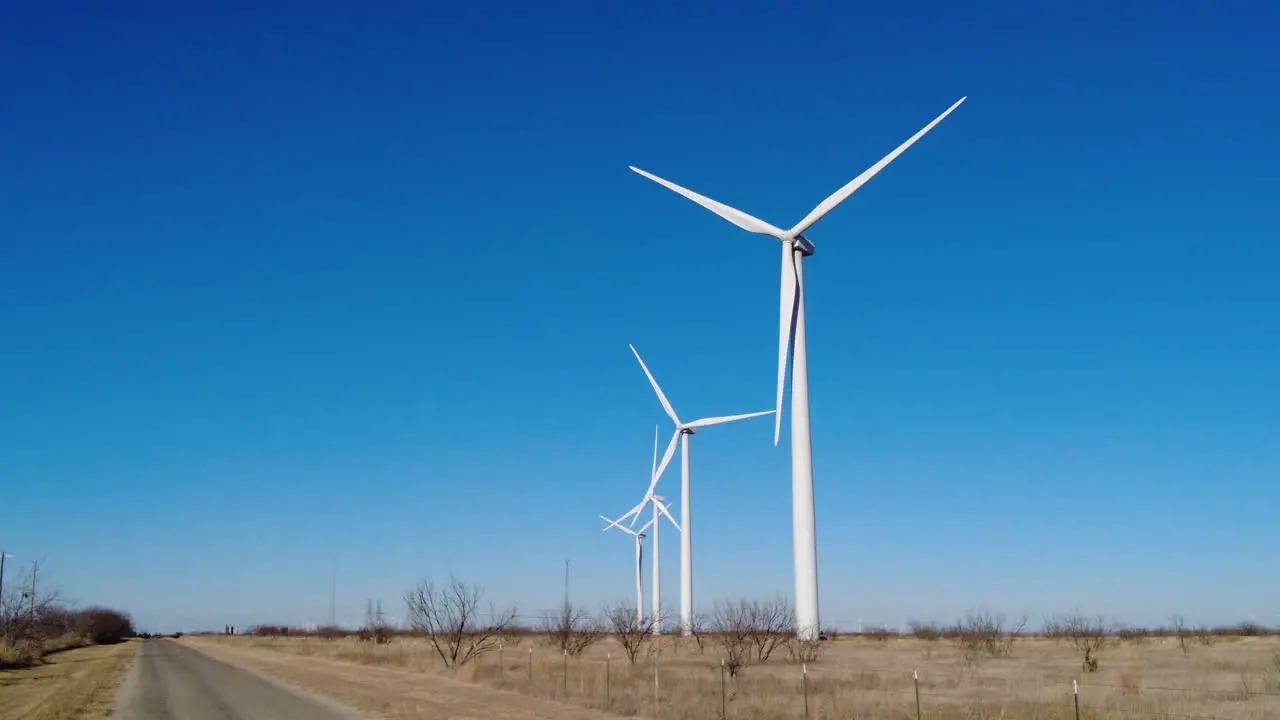 Wind turbines slowly spinning in a field near a road