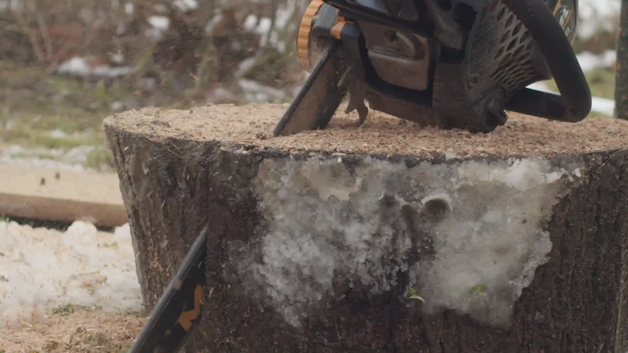 Parallax shot of a chainsaw cutting a piece of wood on a cloudy day