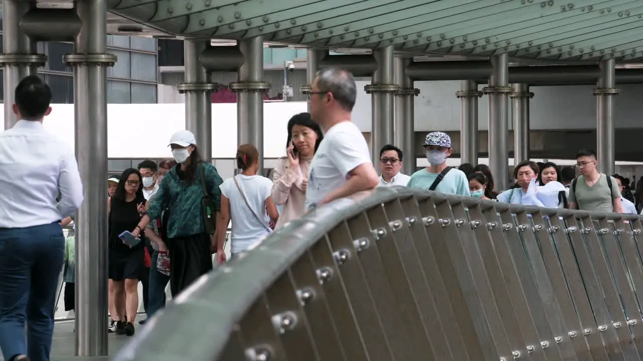 A crowd of pedestrians and commuters walk through a city bride