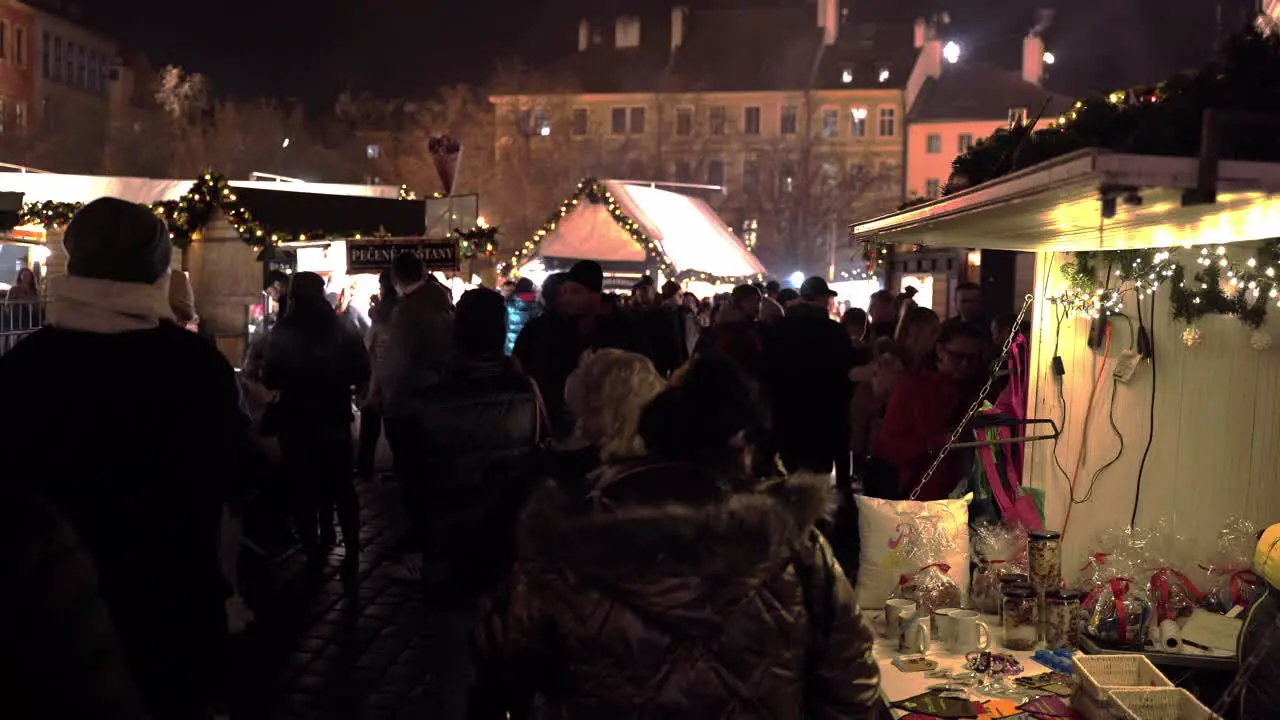 People strolling between Christmas market stalls at night Prague city