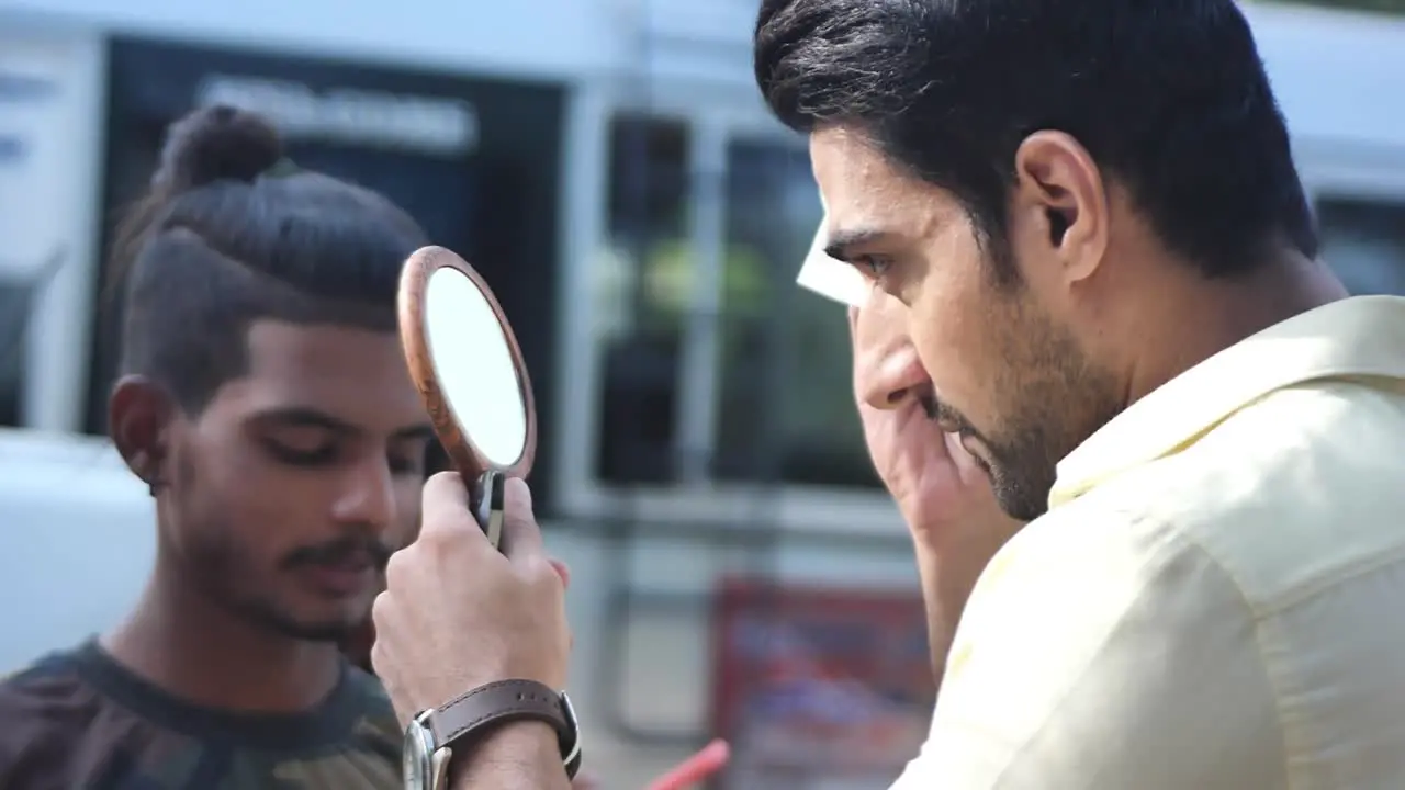 Male Actor Holding Small Mirror Using Tissue To Wipe Face In Karachi Pakistan With Traffic Going Past In Background