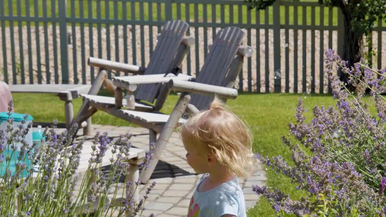 Toddler girl in the backyard playing with soap bubbles slow motion