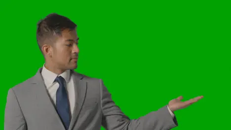 Businessman In Suit Presenting Or Showing Something Against Green Screen 