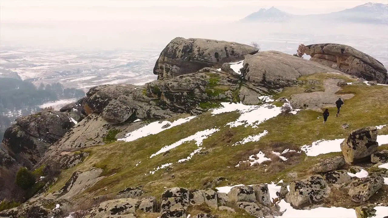 Male and female runners running on a mountain in winter drone shot