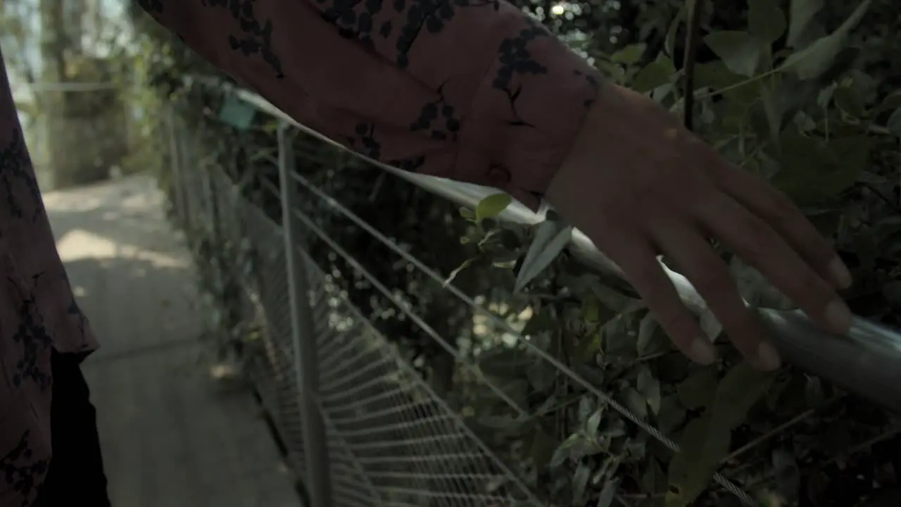 Woman hand touching bridge fence in a beautiful park close up slow motion