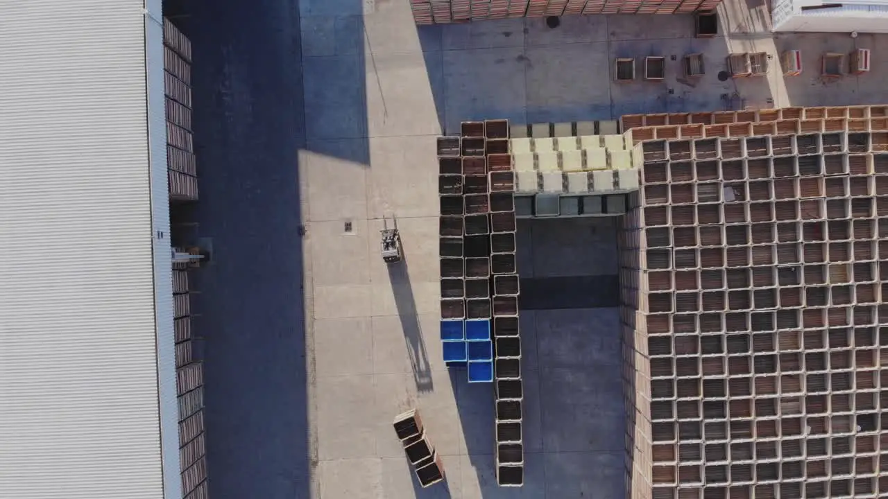 With a gentle ascent the drone unveils the factory property gradually revealing stacks of crates within