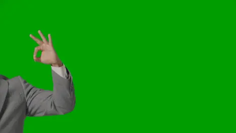 Close Up Of Arm Of Businessman In Suit Giving OK Gesture Against Green Screen 