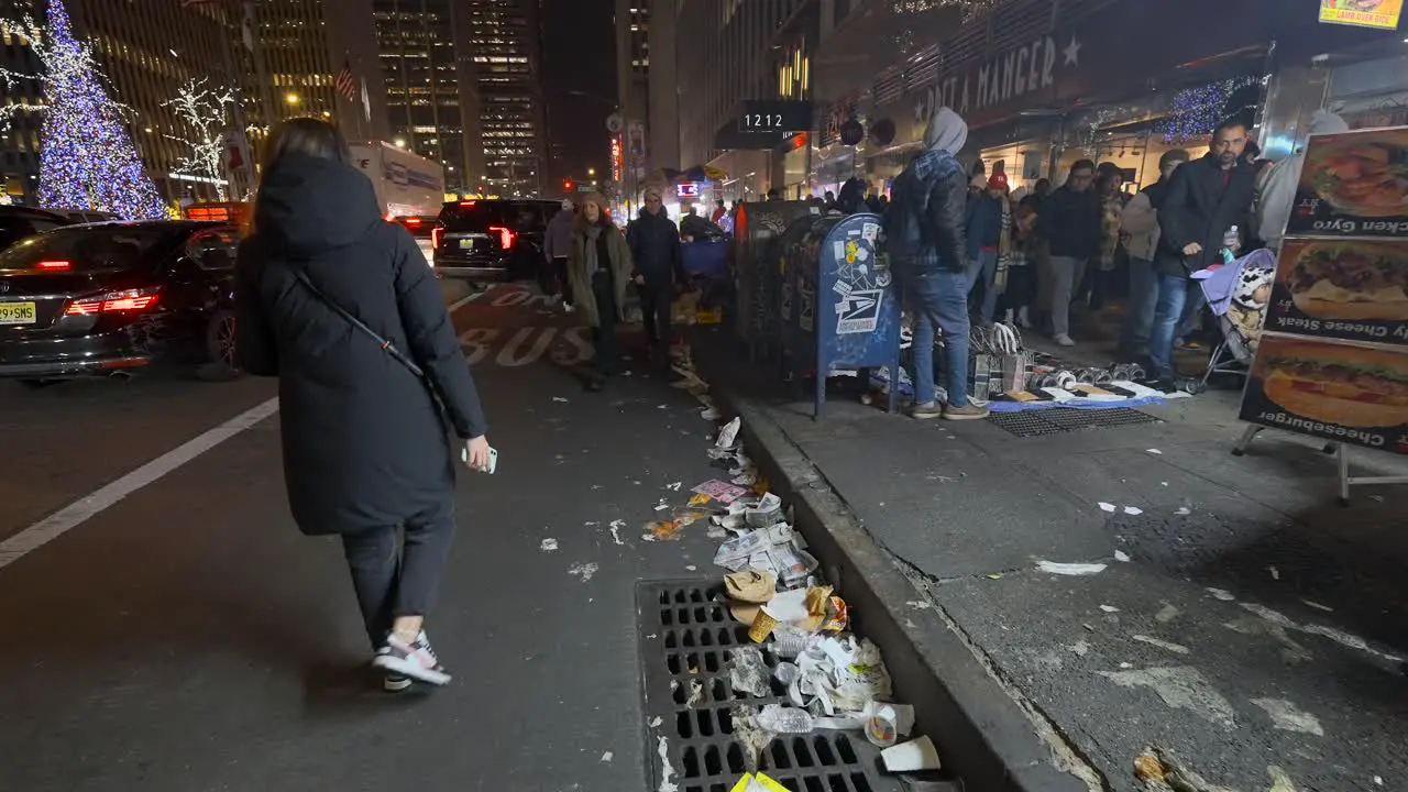 People walking along trash filled street at night in New York City