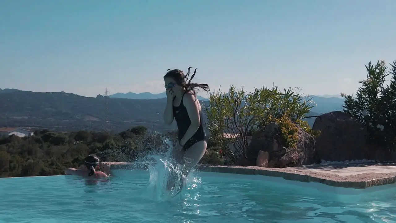 A young girl jumps in to an infinity pool