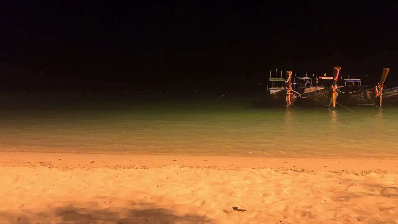 Phi Phi Island at night with long tail boats in the water in Thailand