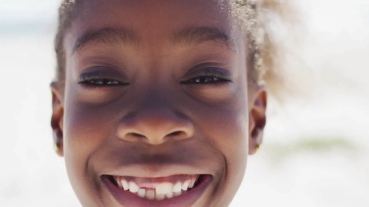 Happy african american girl smiling at camera on beach