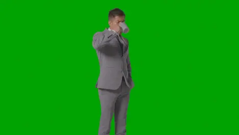 Studio Shot Of Businessman In Suit Holding And Drinking Cup Of Hot Drink Against Green Screen 2