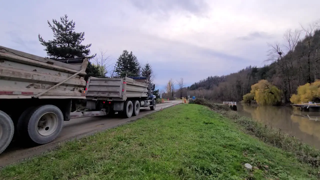 A blue truck with containers driving along the river then took a turn at the end