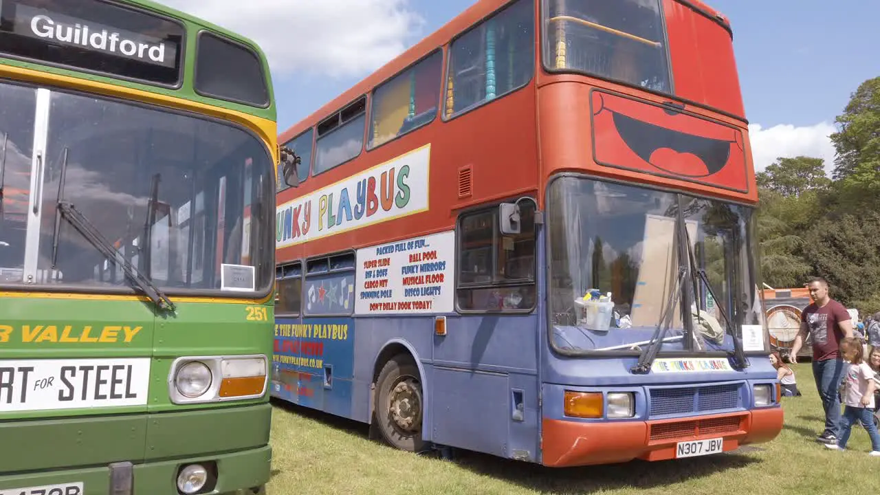 An old fashioned single deck bus next to a double decker bus that has been converted into a kids play area bus