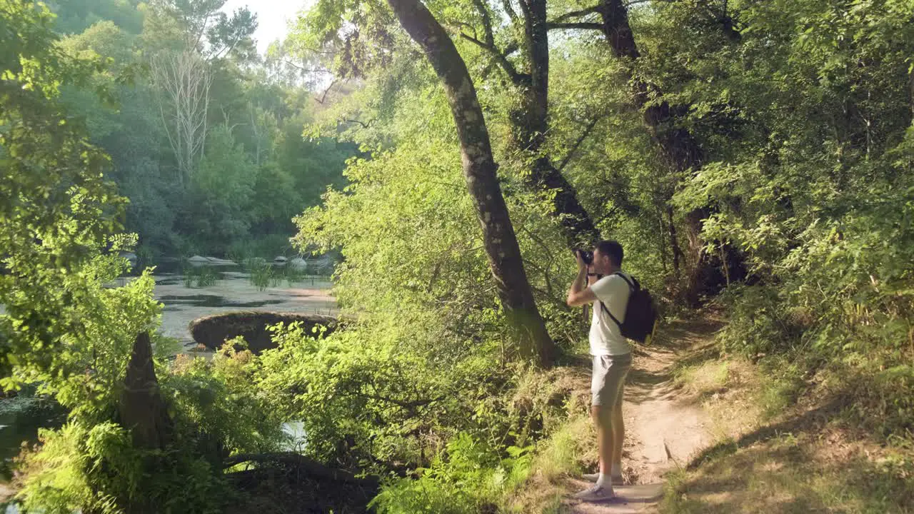 Caucasian adult taking photos outdoors with a professional camera photographer in forest landscape