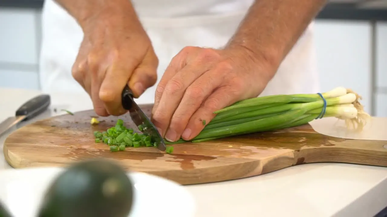 Slicing scallions on cutting board to use as garnish for zoodle dish